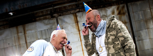 To menn med partyhatt og fløyte. Fotograf Richard K. Johansen To menn med partyhatt og fløyte.