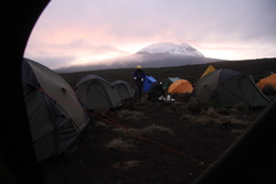 Dette bildet ble tatt klokken 06.15 den første morningen jeg våknet i teltet og i fjellet. Vincent kommer med kaffe, og bak ham får vi et glimt av mektige Kilimanjaro.
