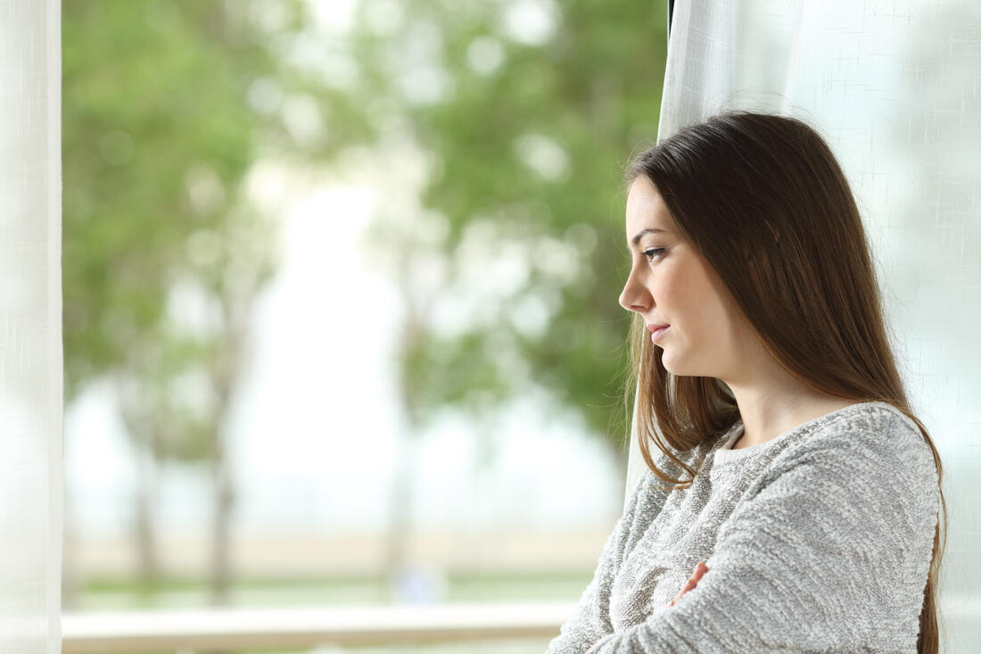 Longing woman looking through window at home