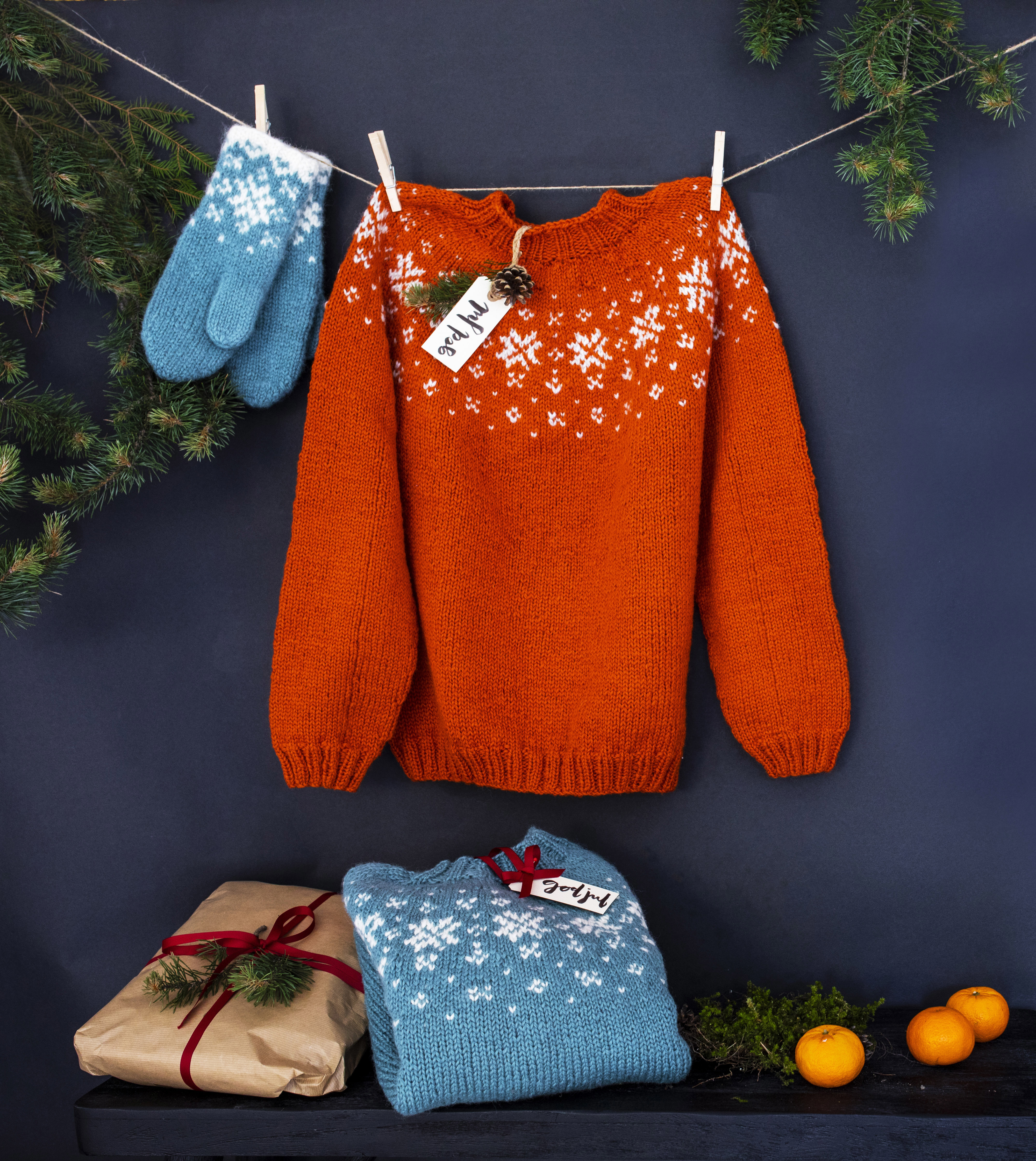 Et blått vottepar og en oransje strikket genser som er hengt opp med klesklyper på ei snor