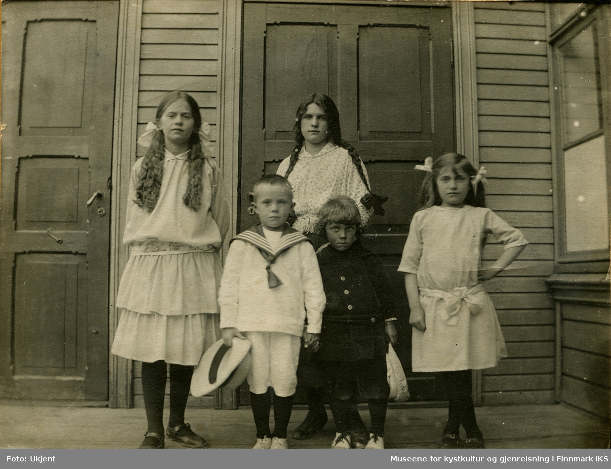 Avbildet er her noen av Maren og Cornelius Moes barn ved inngangen til bestyrerboligen, som tilhørte skolen i Hammerfest. Fra vestre er det Haldis, Kaare, Emma, et fremmed barn og Hildur