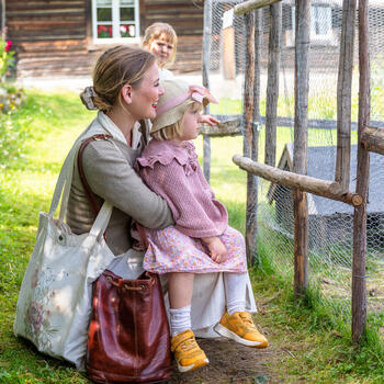 Foto av mor med to barn på Prøysenhuset som ser på kaninene