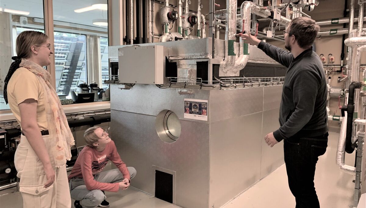 Odne Oksavik (til høyre) forklarer Ada Hagaseth (til venstre) og Bettina Due hvordan PCM-tanken blir varmet opp. Foto: SINTEFblogg