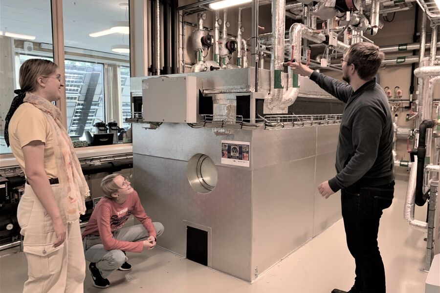 Odne Oksavik (til høyre) forklarer Ada Hagaseth (til venstre) og Bettina Due hvordan PCM-tanken blir varmet opp. Foto: SINTEFblogg