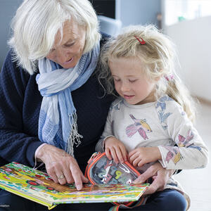 Bilde av eldre dame som leser for lita jente