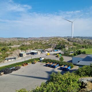 Avfallssorteringsområdet på Svåheia sett i fugleperspektiv, med blå kontainere, og i bakgrunnen er det berg og vindmølle.