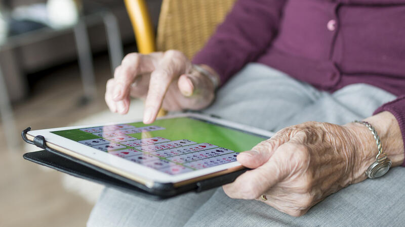 Eldre person som legger kabal på iPad