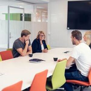 fire mennesker sitter rundt et møtebord og planlegger
