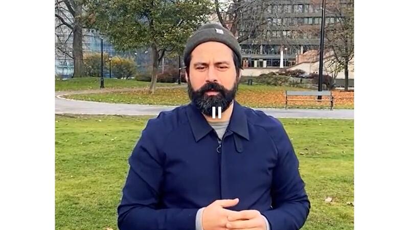 mann med skjegg og topplue blir intervjuet i parken
