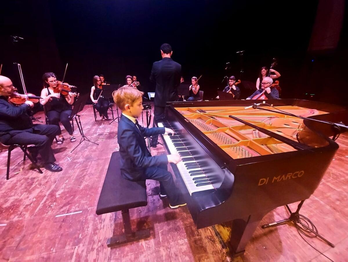 Liten gutt spiller på stor piano med orkester i Roma