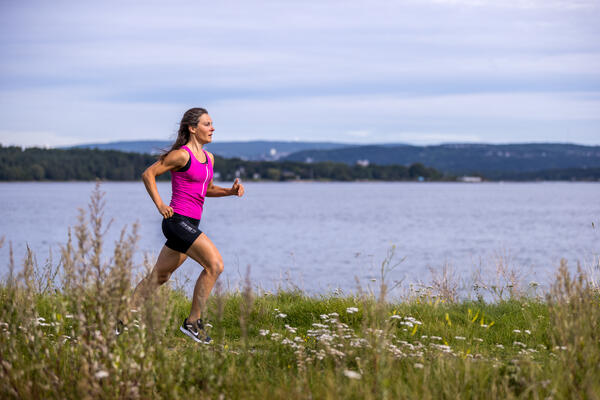 Dame i shorts løper langs grønn eng