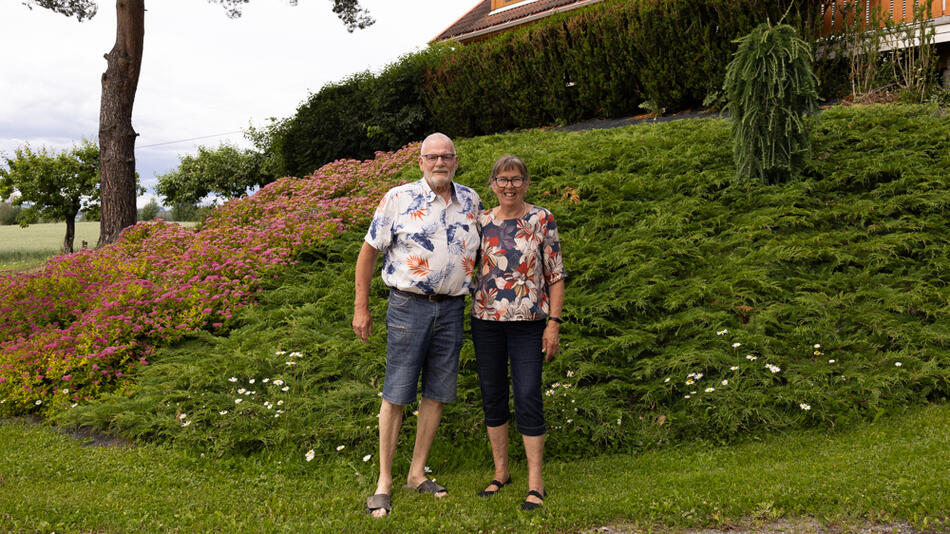 Mann og dame som står foran et blomsterbed