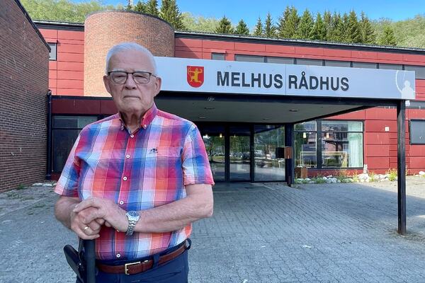 Mann i rutet skjorte står foran inngangen til Melhus kommune.