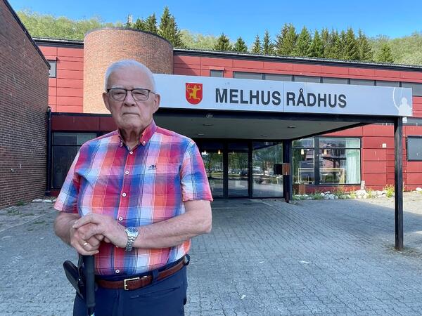 Mann i rutet skjorte står foran inngangen til Melhus kommune.