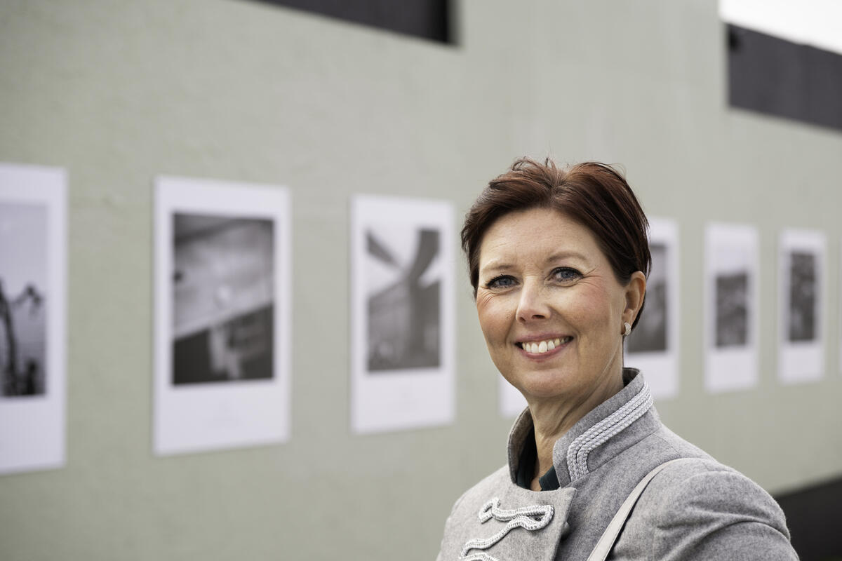 Smilende dame står foran fargerik vegg