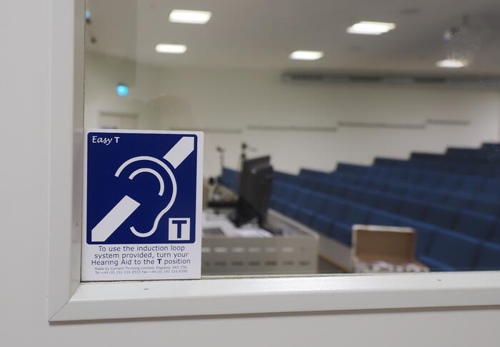 Teleslynge-symbol på dør inn til auditorium, Campus Drammen, USN