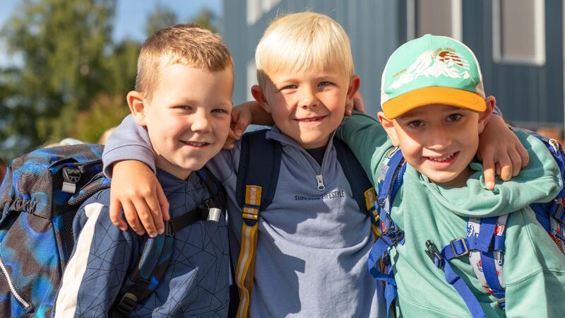 Elever på første skoledag som står sammen