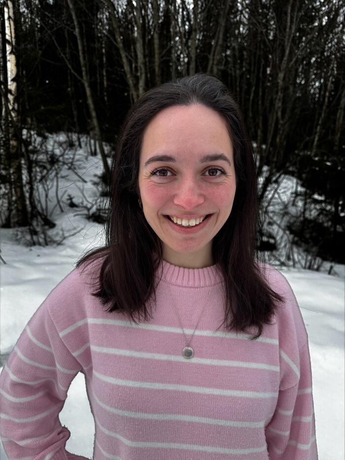 Smilende dame med rosa stripet genser og mørkt hår