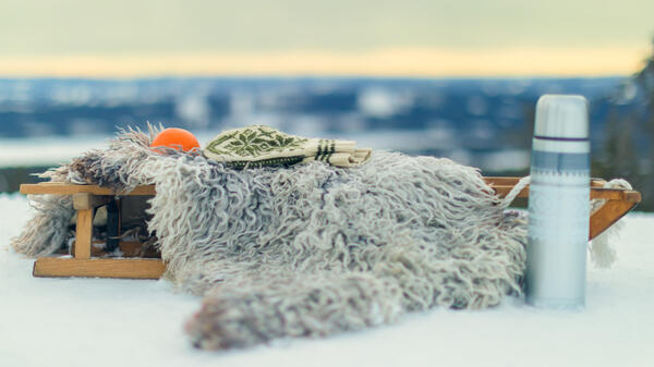 Foto av kjelke i fjellet med appelsin og thermos