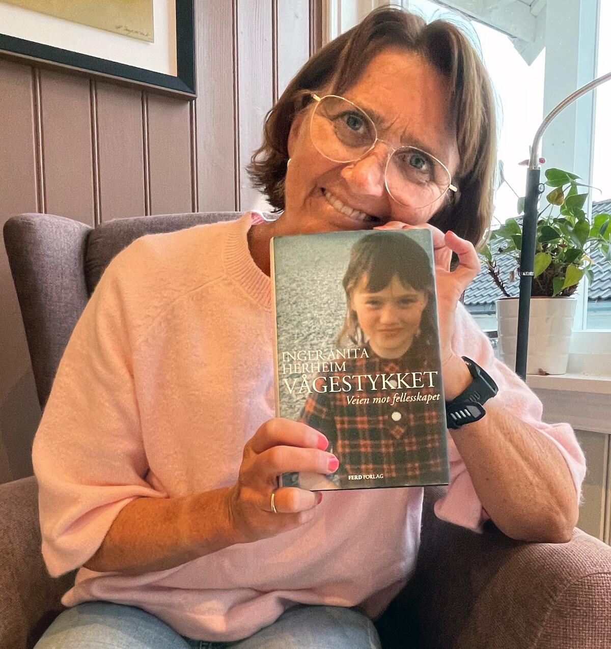 dame viser frem cover på boka Vågestykket