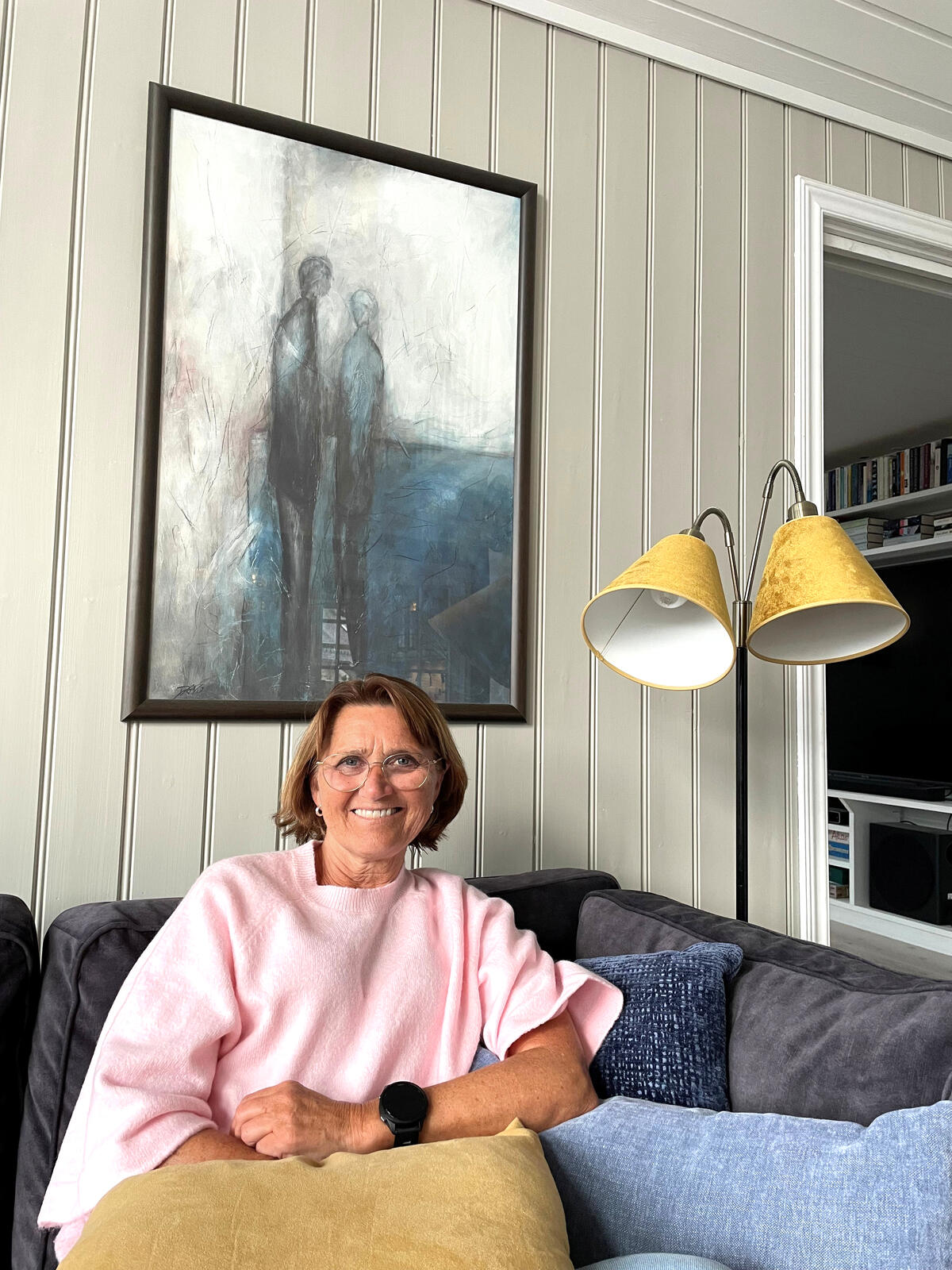 Dame sitter i sofa med pute på fanget