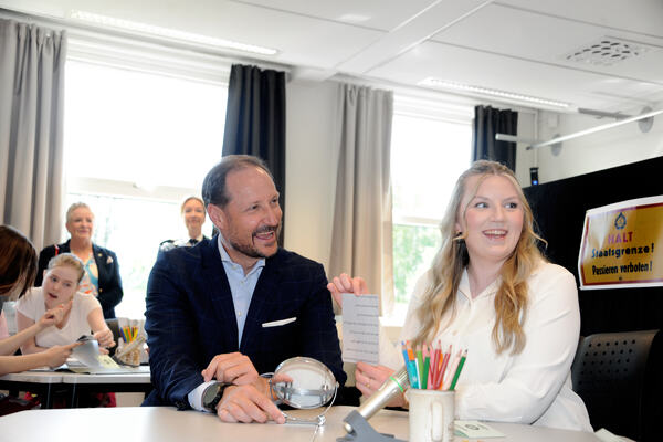 Kronprisn Haakon ler hjertelig sammen med en elev når han klarer å knekke koden