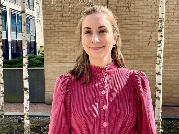 Dame i rosa kjole mot murvegg