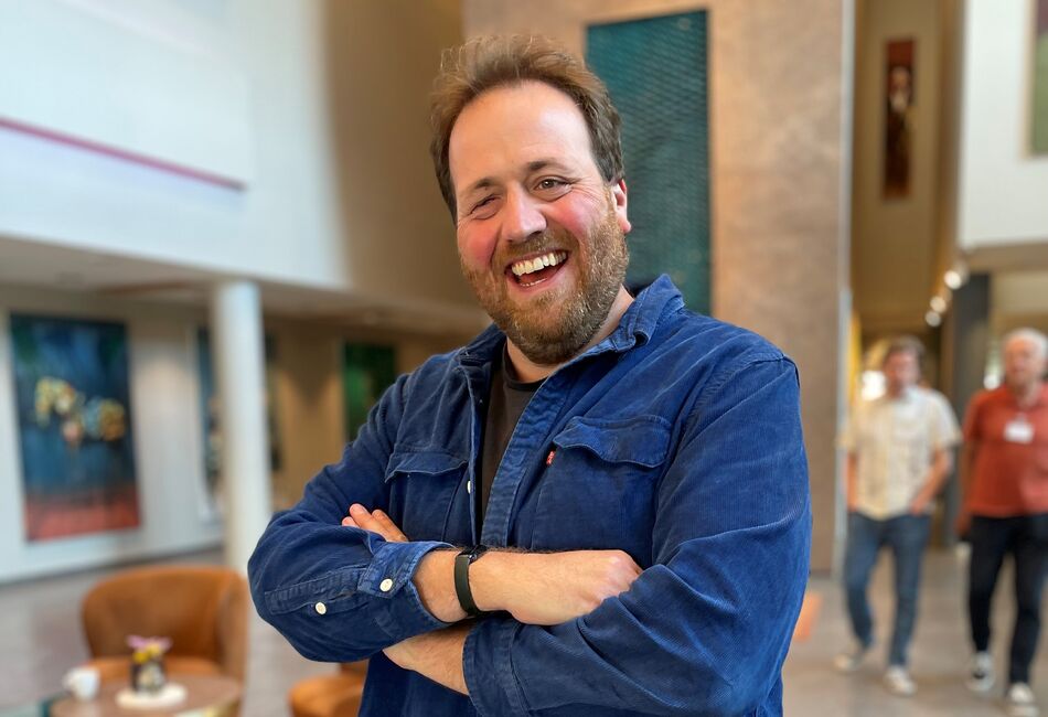 Smilende mann med skjegg og blå dongreijakke