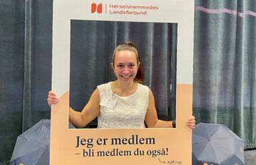 Smilende dame som holder en stor fotoramme rundt seg selv