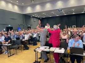 VINKE-APPLAUS. Landsmøtet vedtok å endre navn til Hørselsforbundet, slik sentralstyret har foreslått. Foto: Bjørg Engdahl To damer snur seg mot forsamlingen med hendene i været