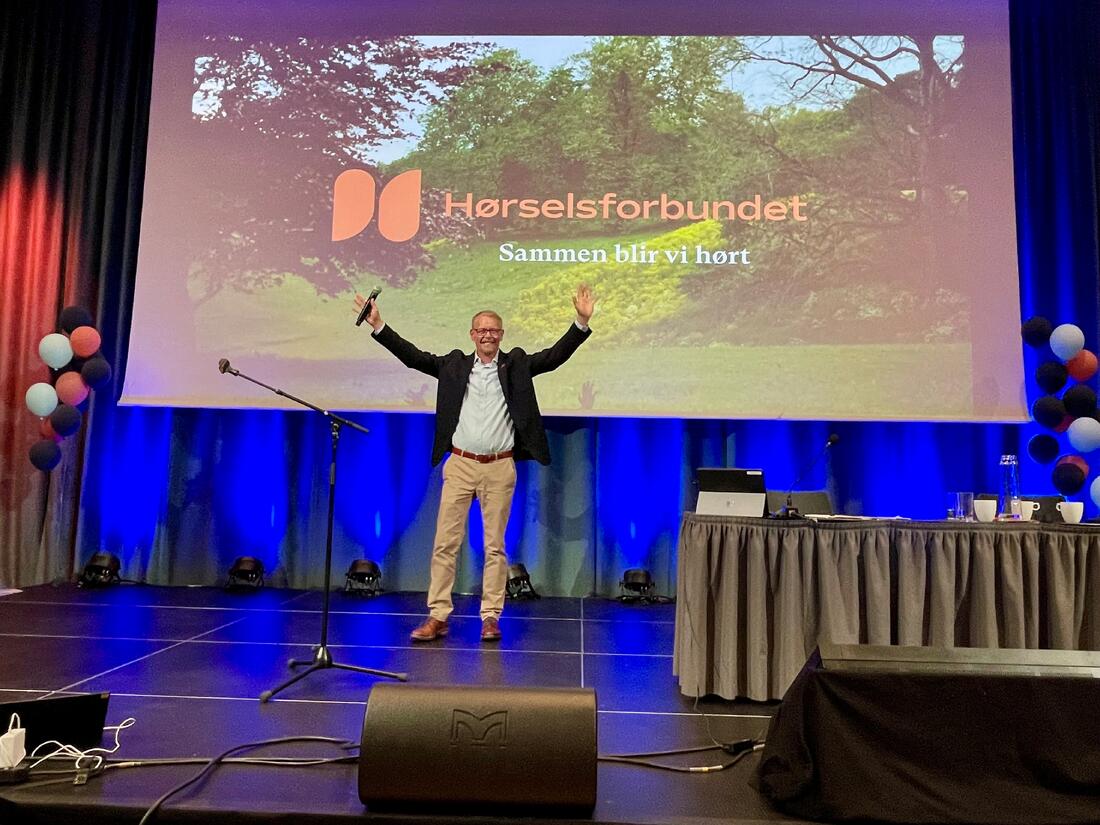 Mann løfter begge hender på en scene