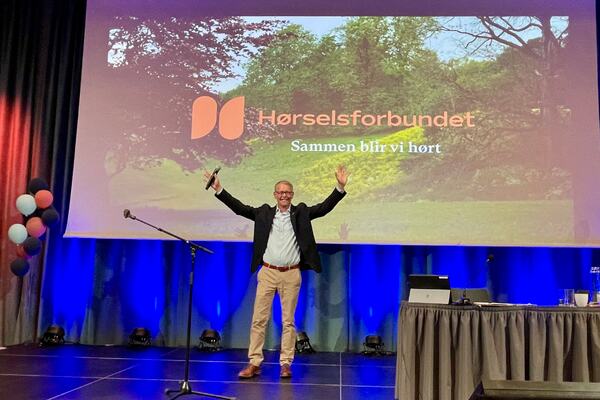 Mann på scenen med løftet hender