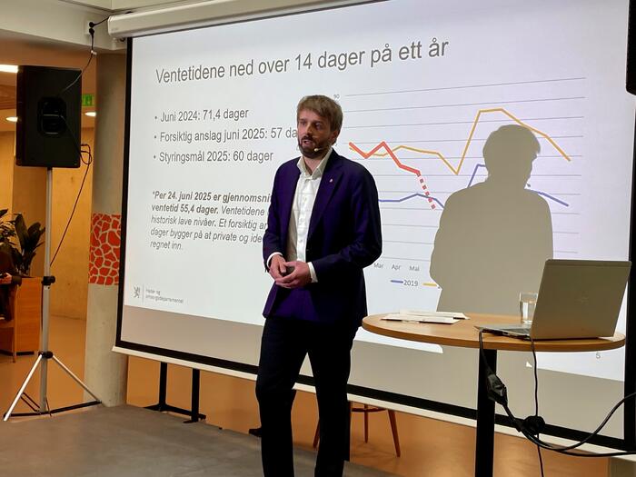 Mann står foran en graf som peker nedover