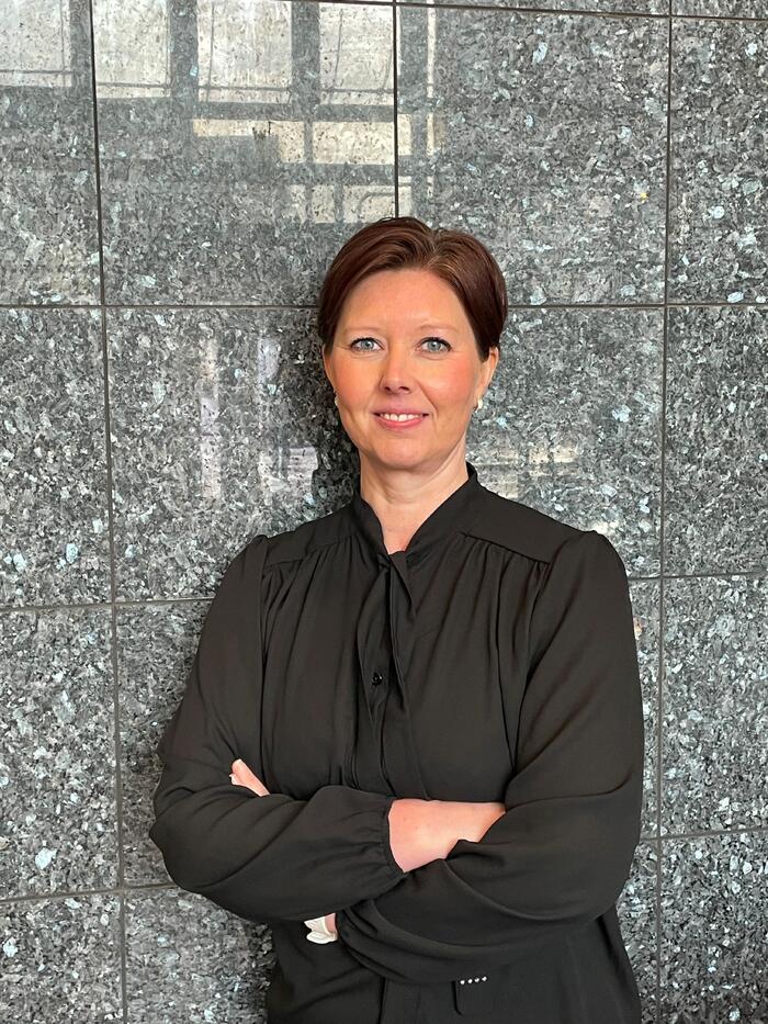 FORNØYD. Audiografforbundets leder Mona Elisabeth Hansen er glad for den varslede effektiviseringen hos Nav. Foto: Bjørg Engdahl Dame står mot grå vegg med hendene i kors