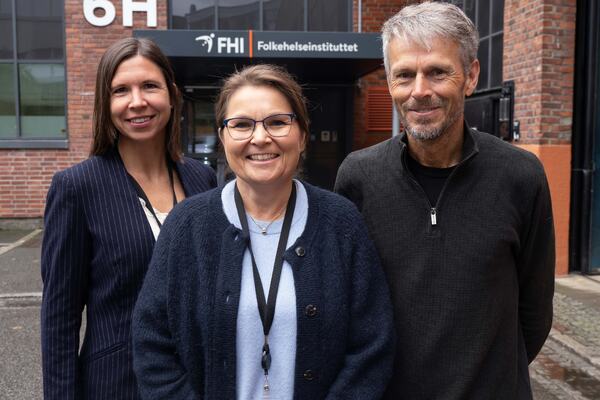 TEGNET KART: Fungerende fagdirektør Hilde Risstad (fra venstre), overlege Ingeborg Lidal og forsker Bo Engdahl har kartlagt forskning om funksjonsnedsettelser som er knyttet til hørsel. Foto: Georg Mathisen. Hilde Risstad, Ingeborg Lidal og Bo Engdahl foran inngangsparti med skilt for Folkehelseinstituttet.