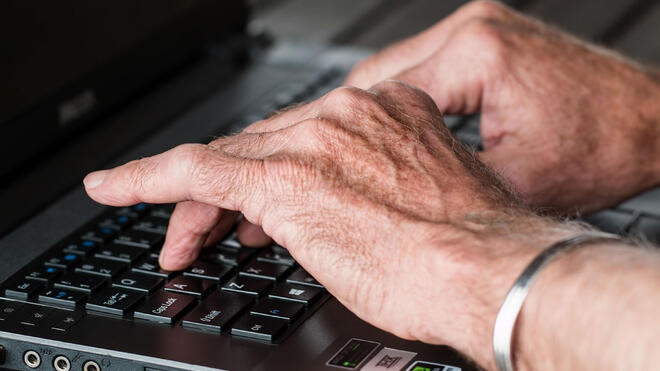 Foto av eldre mann som skriver på en PC