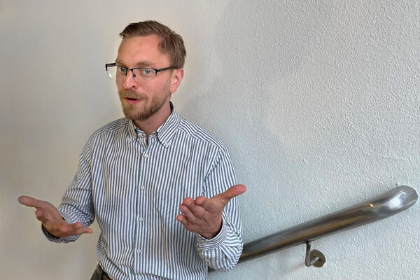 Han ved hvit vegg som gestikulerer med hendene
