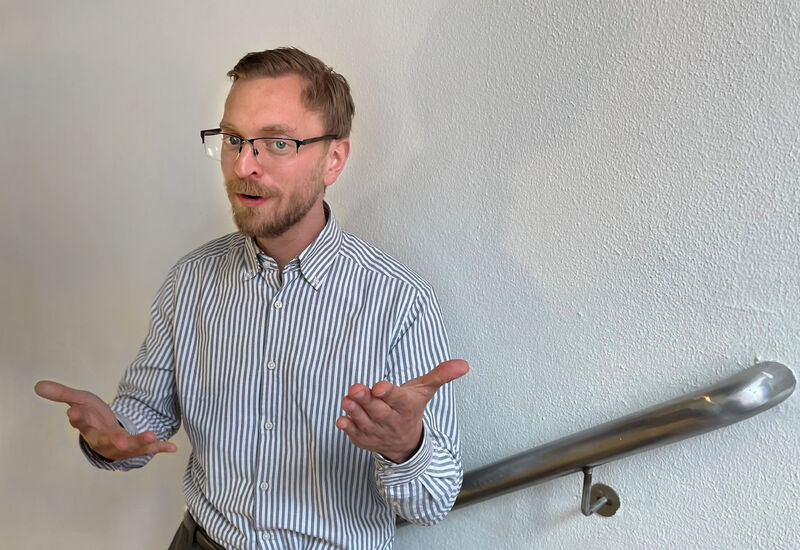 Han ved hvit vegg som gestikulerer med hendene