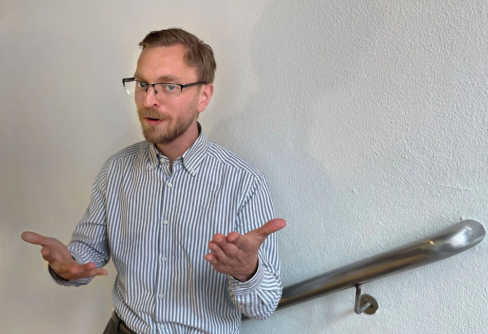 Han ved hvit vegg som gestikulerer med hendene