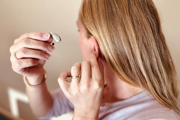 Bilde av dame som er i ferd med å ta på seg høreapparatet.