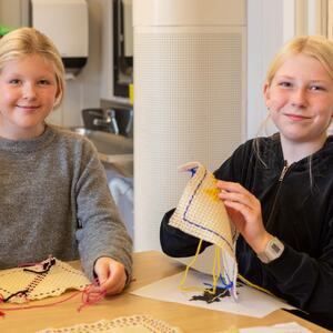 Foto av to jenter som broderer
