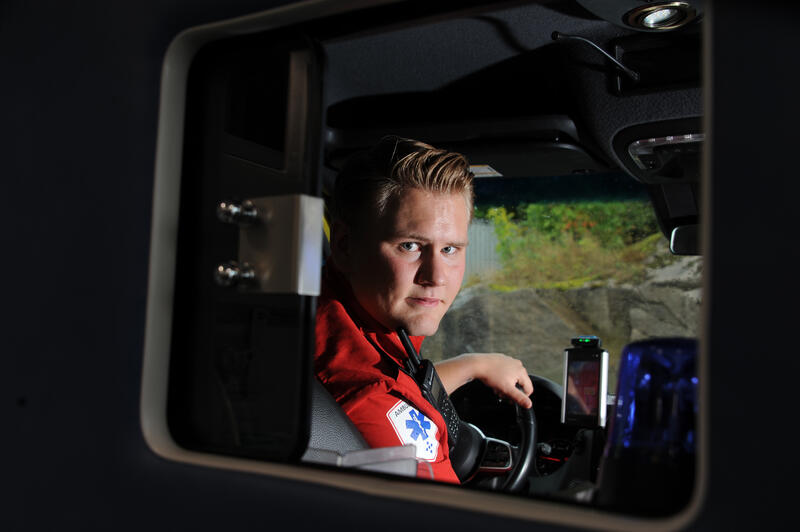 HØRSELEN ER VIKTIG. Det kan være vanskelig å høre hva pasienter med svak stemme sier. For Daniel blir den non-verbale kommunikasjonen ekstra viktig under transporten. Amulansesjåfør snur seg i bilen