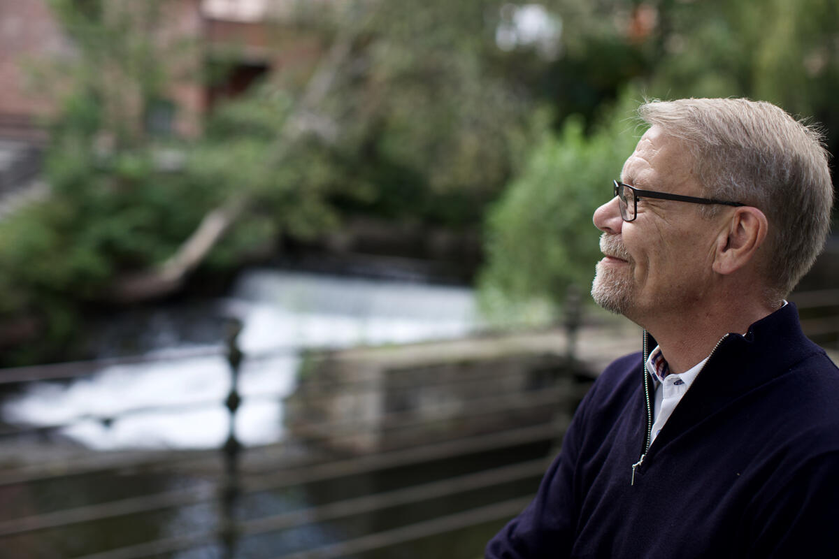 Mann sitter ved brusende elv