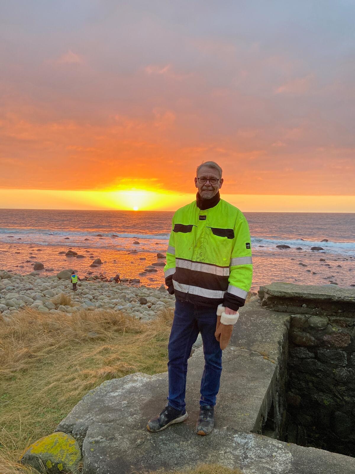 Mann i refleksgul arbeidsjakke ved sjøen