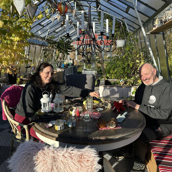 MAnn og dame som sitter ved et bord inne i et drivhus