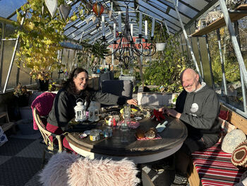 MAnn og dame som sitter ved et bord inne i et drivhus