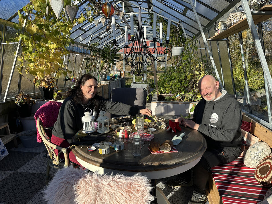 MAnn og dame som sitter ved et bord inne i et drivhus