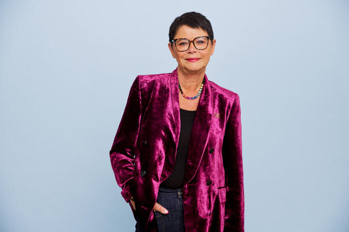 Smilende dame med mørkt, kort hår og rosa jakke