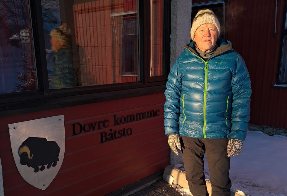 Mann i blå boblejakke står foran Dovre kommunes rådhus