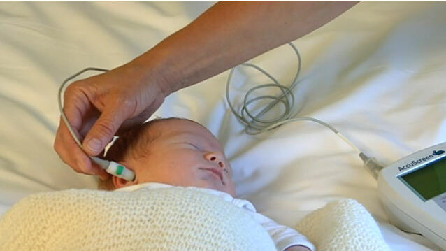 Bilde av nyfødt baby med måleutstyr i øret